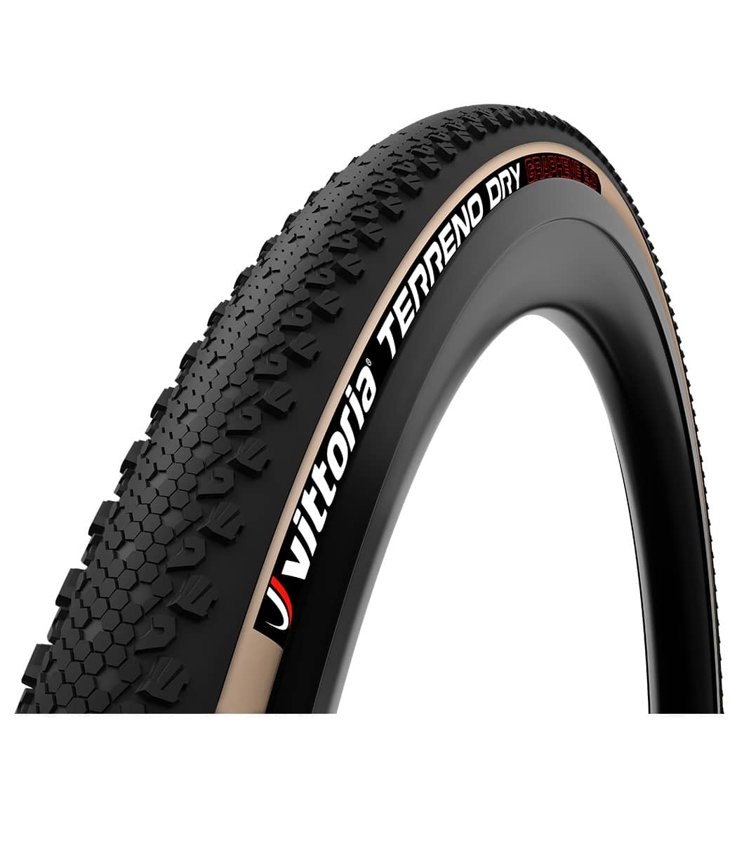 Vittoria-Terreno-Dry-Tan-40-622.jpg Närbild av ett Vittoria Terreno Dry TLR däck monterat på en fälg. Däcket har en brun sidovägg och ett svart mönster. Texten "Vittoria TERRENO DRY" syns tydligt.