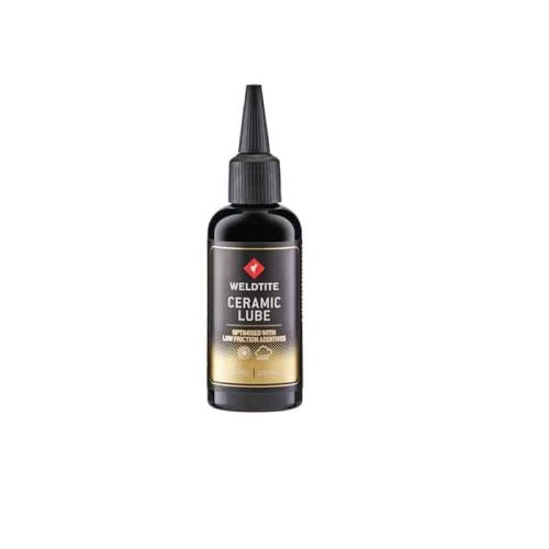 En svart flaska Weldtite Ceramic Lube, etiketten framhäver produkten i tydliga bokstäver och en guldaktig botten, stående mot en ren vit bakgrund i välbelyst atmosfär.