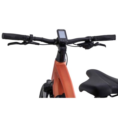 Närbild av styret och skärmen på en orange cykel, med bromshandtag, gasreglage och en del av den vadderade sadeln mot en vit bakgrund.