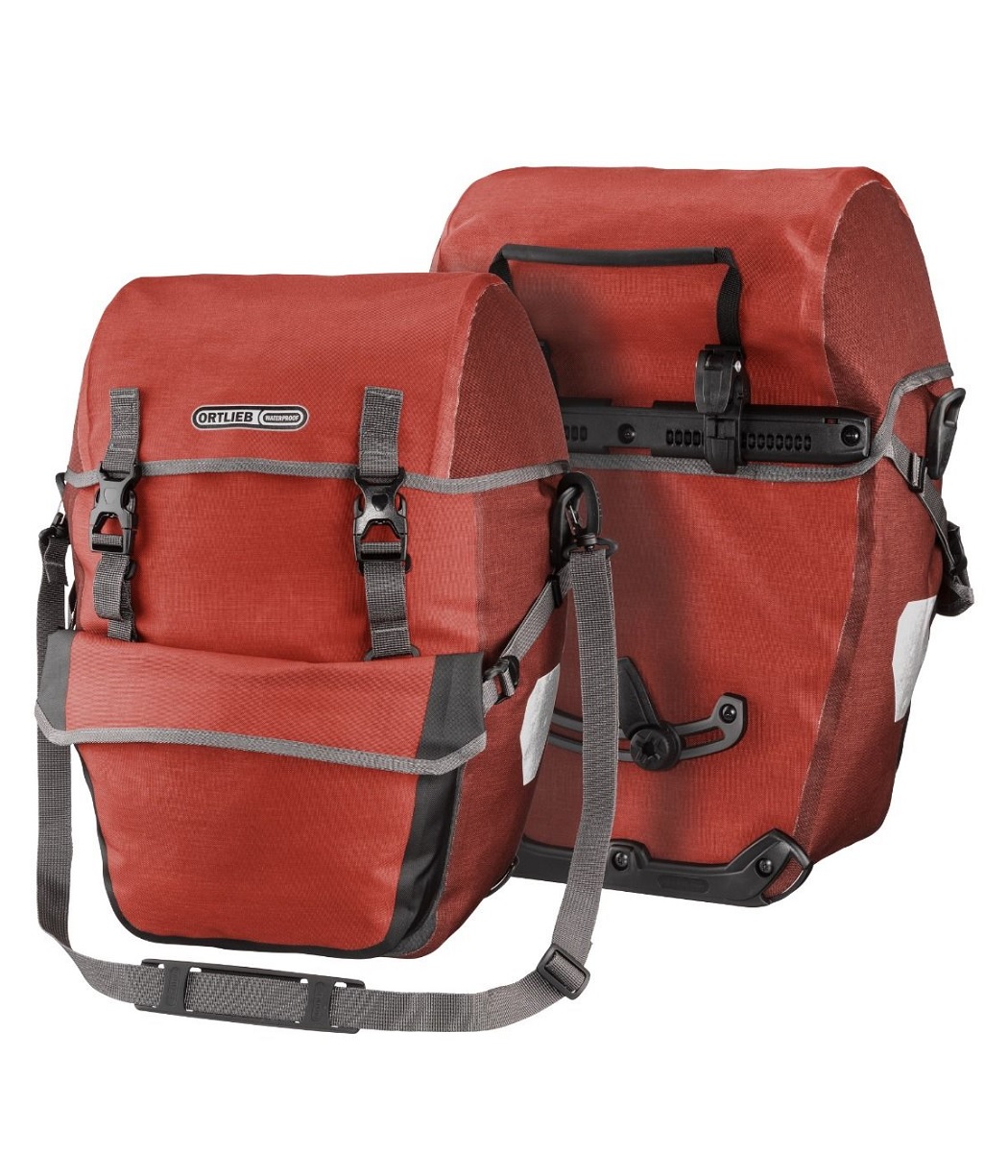 bike-packer-plus-salsa Två Ortlieb Bike-Packer Plus cykelväskor i salsa/mörk chili visas. Väskorna är vattentäta med rullstängning, gråa detaljer och bärrem. Produktbilden har studioljus och detaljerad rendering.