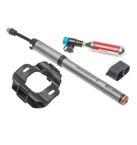 En detaljerad bild visar en Blackburns Core CO2’Fer minipump, tillsammans med tillbehör som fäste och kolsyrepatron. Studioljus framhäver produktens silverfärg och design.