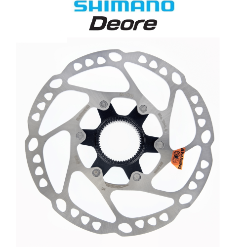 Bromsskivan Shimano Deore SM-RT64, centrerat på vit bakgrund under neutral belysning, framhäver dess perforerade design och svarta mittnav med noggranna skruvdetaljer och en orange varningsetikett.