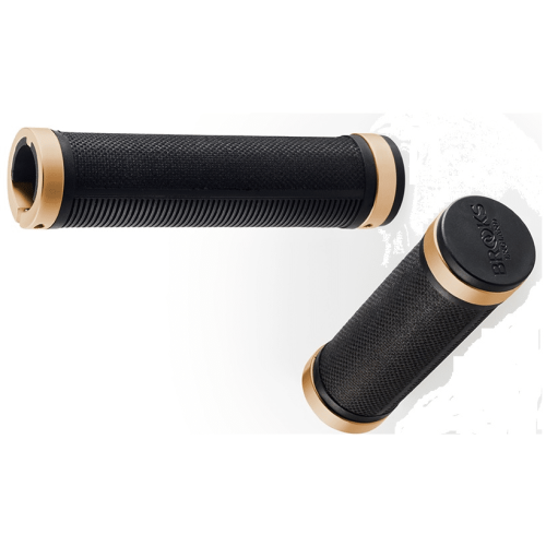 Två handtag, Brooks Cambium Rubber, i svart och guld. Det ena ligger vågrätt med räfflad yta, det andra stående med en mer texturerad yta och logotyp. Mjukt ljus.