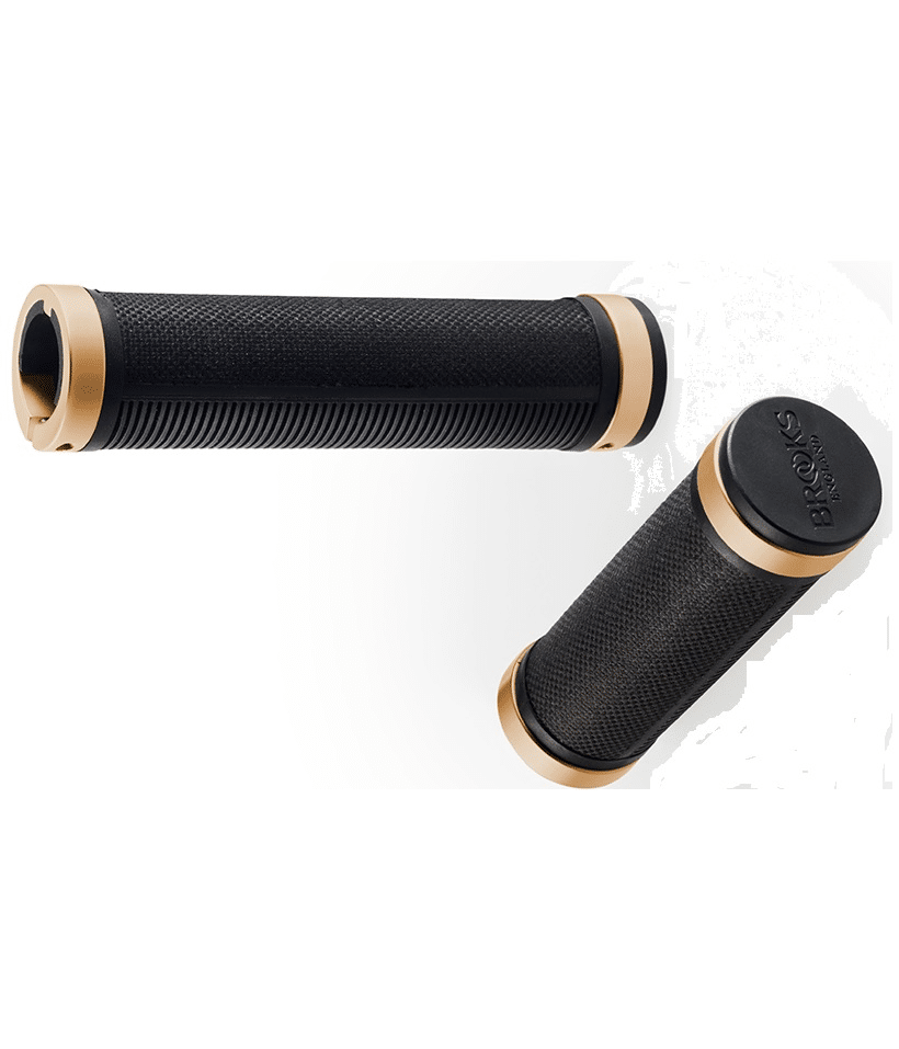 brooks-styrlinda-handtag-svart-koppar.png Två handtag, Brooks Cambium Rubber, i svart och guld. Det ena ligger vågrätt med räfflad yta, det andra stående med en mer texturerad yta och logotyp. Mjukt ljus.