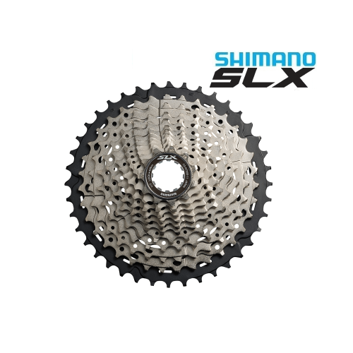 Cykelkassett Shimano SLX CS-M7000 med 11 växlar visas centrerad mot en vit bakgrund. Produktnamnet Shimano SLX syns tydligt i övre högra hörnet med blå och svarta bokstäver. Metalliska detaljer är väl synliga.