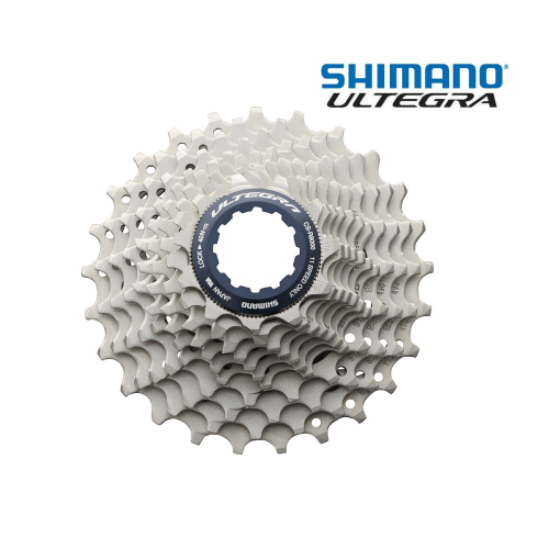 Detaljerad bild av en Shimano Ultegra CS-R8000 11-växlad kassett. Kassetten är silverfärgad med blå detaljer. Marken är vit och bakgrunden är ljus.