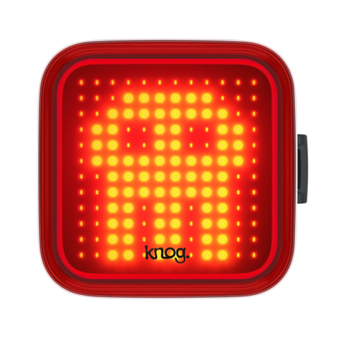 Knog Blinder Skull baklampa är en fyrkantig röd LED-cykellampa med en pixelerad gul spökdesign, rundade kanter, en sidoknapp och "knog." tryckt längst ner i mitten.