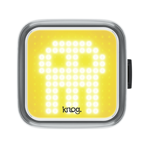 Framlampa Knog Blinder Skull är en fyrkantig cykellampa med gult ansikte och ett vitt pixelerat spökmönster. Varumärket "knog." visas längst ner i mitten.