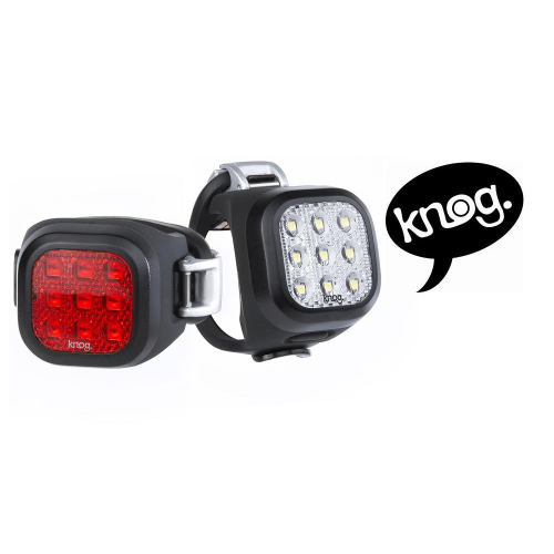 Närbild av Knog Blinder Mini Niner Twinpack fram- och baklampa. Lamporna är i svart med rött respektive vitt ljus. Logotypen "knog." syns i pratbubbla.