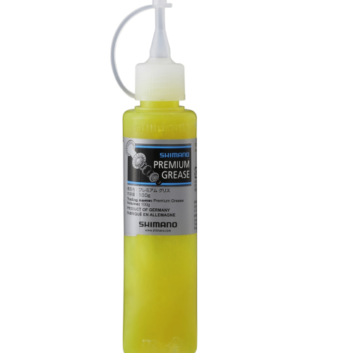 Shimano Premium Grease-flaska med gulaktigt innehåll och vit applikator. Etiketten indikerar "PRODUCT OF GERMANY". Stående mot en ren, vit bakgrund med mjuk belysning. Passar för användning på cyklar.