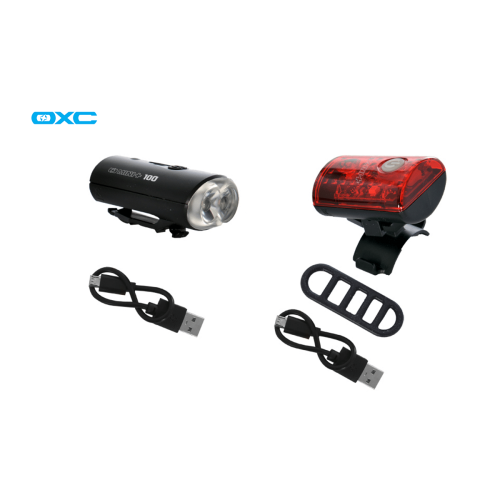 Lampset OXC Mini+ är ett svart cykelljusset med en vit framlampa, en röd baklampa, två USB-laddningskablar och en svart monteringsrem, allt mot en vit bakgrund.