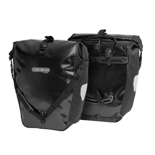 Två Ortlieb Back-roller packväskor i svart (2x20 liter), vattentäta med sidospännen och reflexer, visas fram och bak på vit botten. Den ena väskan har Ortliebs logotyp, den andra visar sitt monteringssystem.