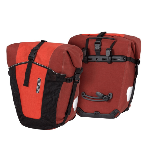 Bilden visar två Ortlieb Back-Roller Pro Plus packväskor i rött - den ena med logotyp och nätficka på framsidan, den andra med monteringsbeslag och bärhandtag. Båda har svarta remmar och vita reflexer.