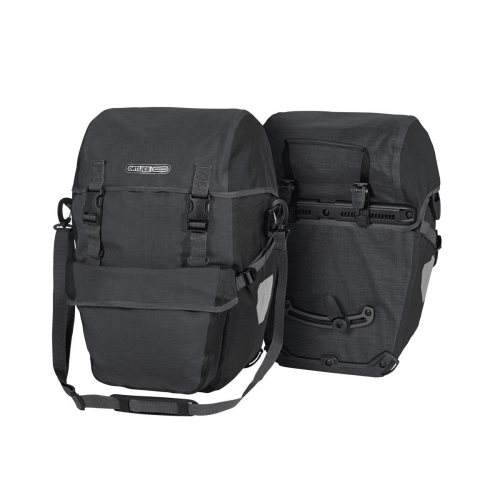 Bilden visar två Ortlieb Bike-Packer Plus-väskor i granit/svart (42L): den ena visar sina spännen och axelrem, den andra visar monteringssystemet för cykelhållaren.