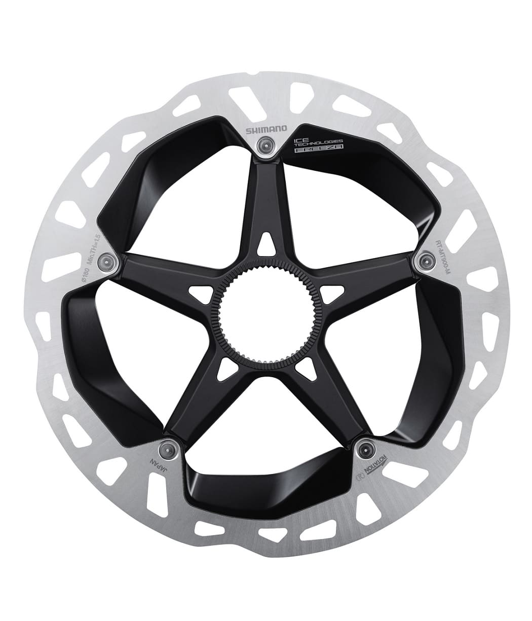 p-rt900-ut.jpg Detaljerad bild av en Shimano XTR/Dura Ace RT-MT900 bromsskiva. Skivan har en silverfärgad yttre ring och ett svart centrum med en stjärndesign. Den presenterar varumärkesmärkningen och produktmodellbeteckningen i tydliga detaljer.