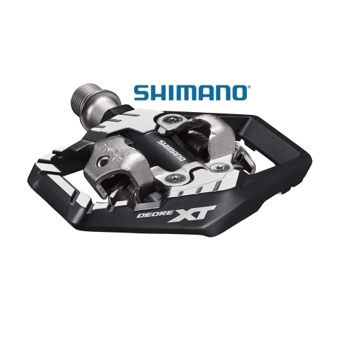 Detaljerad bild av en Shimano XT PD-M8120 SPD-pedal. Fokus på metallkonstruktionen och den svarta plattformen med 'DEORE XT' tryckt i vitt. Studioljus framhäver detaljerna.