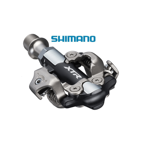 Detaljerad bild av en Shimano XTR PD-M9100 SPD-pedal. Ljuset framhäver den silvergrå och svarta färgschemat. Skärpan möjliggör tydlig granskning av fjädrar, skruvar och XTR-logotypen.