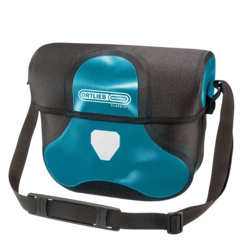 Ortlieb Ultimate Six Classic 7 liter är en blå och svart vattentät axelremsväska med en lång justerbar rem, frontklaff, vit reflekterande patch och visar Ortliebs varumärke med en "Classic"-etikett på framsidan.