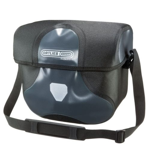Ortlieb Ultimate Six Classic 8,5 liter är en svart och grå vattentät axelremsväska med frontklaff, justerbar rem och en framträdande logotyp på framsidan.