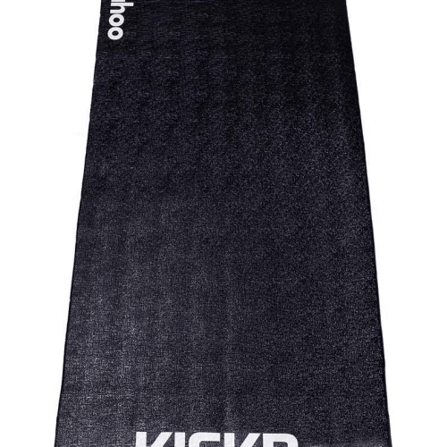 En svart träningsmatta med "wahoo" skrivet vertikalt upptill och "KICKR" horisontalt nedtill, fotograferad mot en vit bakgrund i bra belysning.