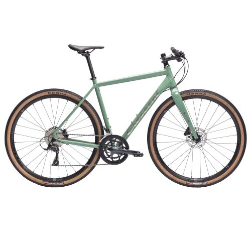 Grön Crescent Grus Sport G4 gravelcykel i studioljus. Fokus på det breda däcken med "G+" och "KENDA" synligt. Belysningen framhäver cykelns detaljer och den ljusa bakgrunden bidrar till ett rent utseende.