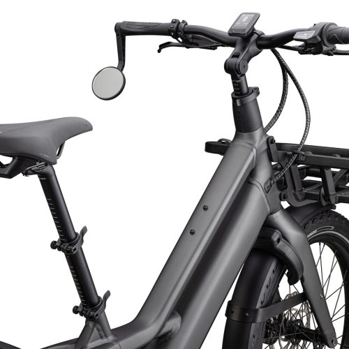 En mattgrå elcykel visas i en studio med jämnt ljus, detaljerade komponenter som sadel, styre med display och en frontmonterad lastkorg framhävs i bilden.