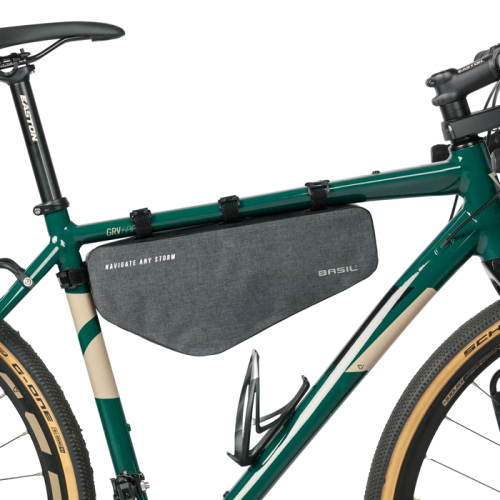 En grå Basil Navigator Storm M ramväska monterad på en grön cykel med beige detaljer. Väskan är fäst med svarta band och har texten "NAVIGATE ANY STORM" och "BASIL". Ljuset är jämnt fördelat.