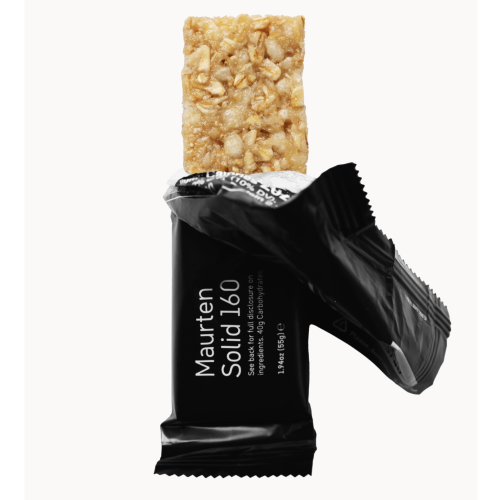 En öppnad Maurten SOLID 160 energibar visas, den övre delen blottad. Stapeln har en gyllene färg och innehåller oats. Bar-förpackningen är svart och texten syns tydligt.