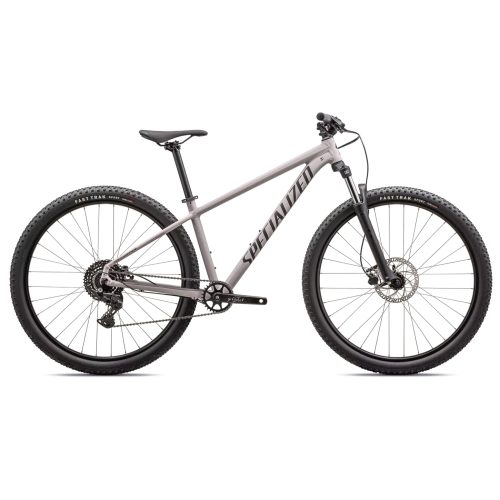 En grå Specialized Rockhopper Sport mountainbike står i bra ljus mot en vit bakgrund, vilket framhäver dess sportiga design och moderna detaljer. En perfekt MTB för äventyr.