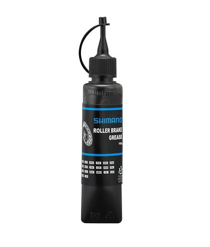 ROLLER-BRAKE-GREASE Närbild av en svart flaska Shimano rullbromsfett, 100 gram. Etiketten är blå och vit med texten "Shimano Roller Brake Grease". Stämningen är professionell och ljuset är jämnt fördelat.