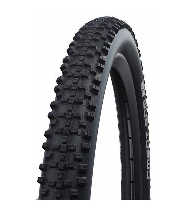 Schwalbe-smart-sam-27 Ett Schwalbe Smart Sam 27,5x2,25" MTB-däck, monterat på en fälg, ses i en produktfotografering. Däcket domineras av ett tätt mönster av fyrkantiga knoppar. Ljuset är jämnt fördelat och ger en detaljrik återgivning av däcket.