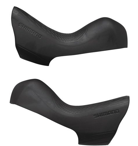 Två svarta Shimano Ultegra ST-R8020 reglage skydd visas mot en ren vit bakgrund. Fokus ligger på detaljerna i gummit och den präglade "SHIMANO" logotypen. Mjukt, diffust ljus framhäver texturerna.