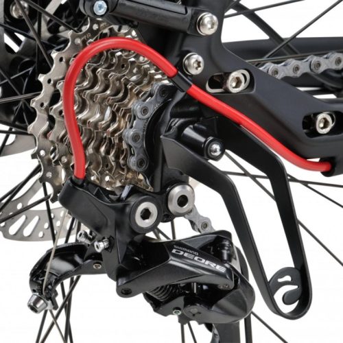 Närbild av ett växelskydd monterat på en cykel, med fokus på Shimano Deore-växeln och den röda skyddsbågen. Detaljerad bild av kassetten, kedjan och cykelns ram i mjuk belysning.