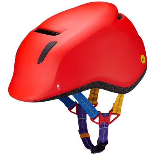 Röd cykelhjälm med slät matt yta, svarta ventilationsöppningar och en mångfärgad justerbar hakrem med blå, röda och gula delar. Hjälmen har ett litet gult säkerhetsdekaler på sidan.