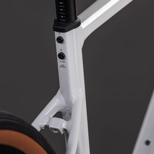 Detalj av vita Cube Nuroad EX cykelramen, sadelstolpe med bultar och däck.