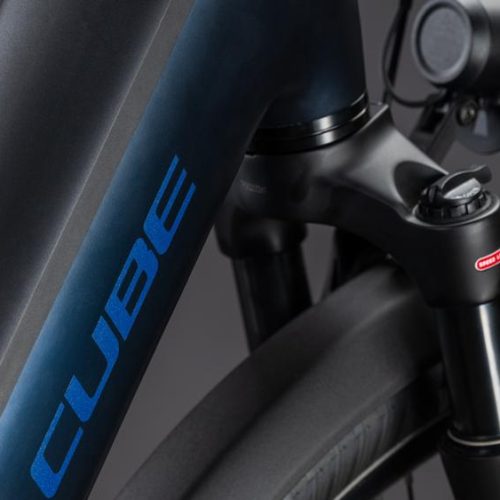 Detalj av blå Cube Supreme Hybrid Deluxe elcykel med framgaffel och däck.