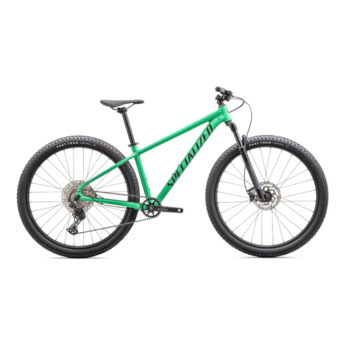 En grön mountainbike med svart sadel, svart styre och svarta däck, sedd från sidan mot en vit bakgrund. Ordet "Specialized" är tryckt på ramen.