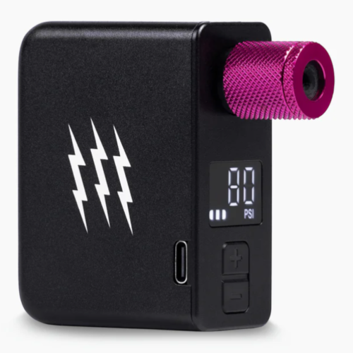 Elektrisk Pump Muc-off AirMach Electric Mini Inflator - Pro är en kompakt svart enhet med tre vita blixtar, en digital display som visar "80 PSI", kontrollknappar, en USB-C-port och ett metalliskt lila cylindriskt toppfäste.