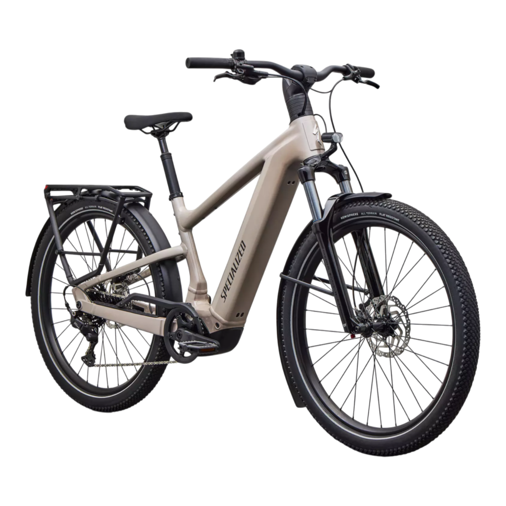 En Specialized Vado 3.0 elcykel i beige med en robust ram, svarta hjul, skivbromsar, lasthållare bak och fjädring fram visas på en vit bakgrund.