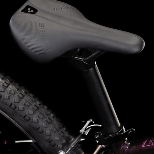 Närbild på en Barncykel Cube Acid 240 24" 1x7s – Lila cykel, där sadeln med ”Cube”-logotypen, sadelstolpen och det knubbiga mönstret på bakdäcket syns mot en svart bakgrund.