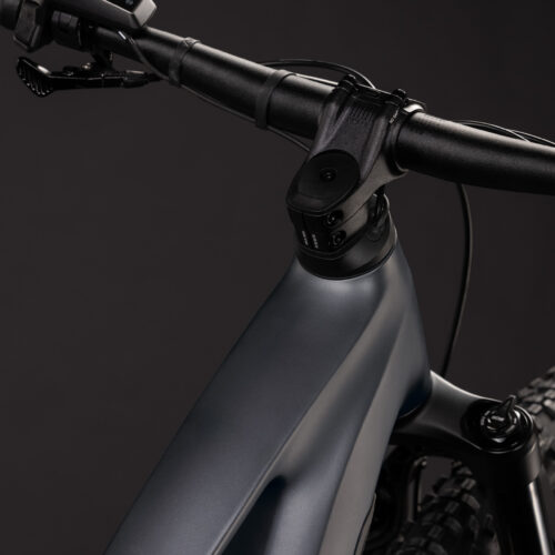 Närbild på El-MTB Cube Stereo Hybrid ONE22 PRO 800 – Grås mattsvarta styre, styrstam och främre ramdel mot en enfärgad mörk bakgrund, med en delvis vy av den främre fjädringsgaffeln och mönstret på framdäcket.