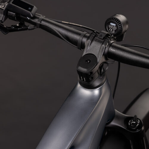 Närbild på styret, styrstammen och den främre delen av styrröret på El-MTB Cube Stereo Hybrid ONE22 PRO FE 800 – Grå, där de monterade reglagen och kablarna framhävs mot en mörk bakgrund. Cykeln har en mattgrå ytbehandling och ett modernt, välskött utseende.