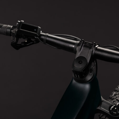 Närbild på styret på El-MTB Cube Stereo Hybrid ONE22 SLX 800 – Svart, där man ser styret, handtagen, kontrollskärmen och en del av framhjulet, mot en enfärgad svart bakgrund.