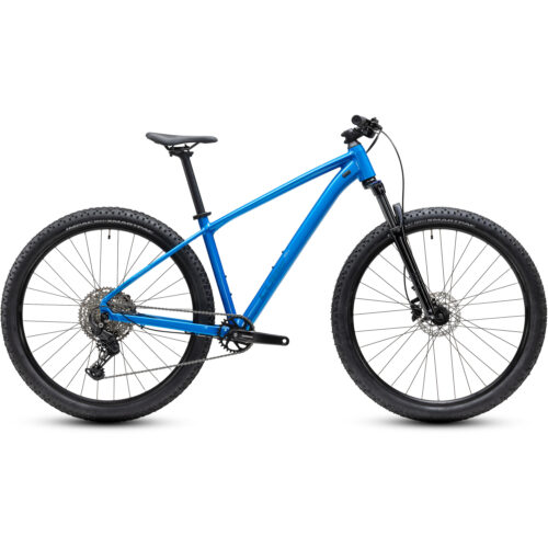 En blå MTB 27,5 Cube Aim PRO-mountainbike med hardtail-ram, framgaffel med fjädring, rakt styre, skivbromsar och grovmönstrade däck visas i profil mot en vit bakgrund. Cykeln är utrustad med en Shimano Cues 1x11-drivlina och finns i grått eller blått.