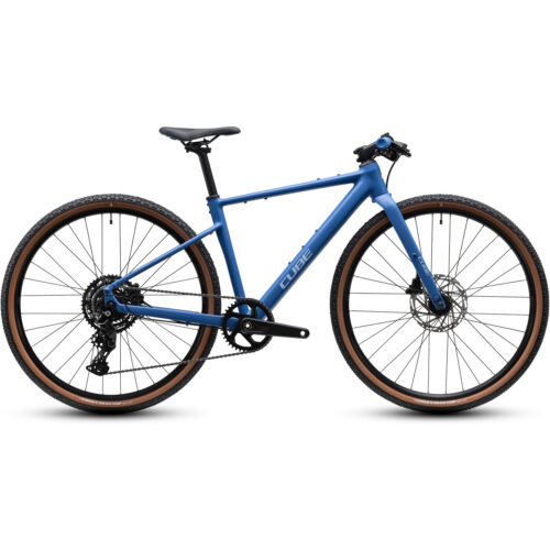 En blå Barncykel Cube Nulane Rookie ONE 28″ 1x9s-cykel med rakt styre, svart sadel, skivbromsar och däck med bruna kanter, fotograferad från sidan mot en vit bakgrund.