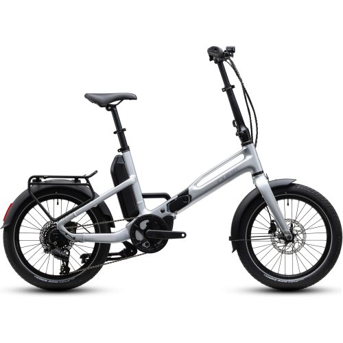 En silverfärgad, hopfällbar elcykel med svarta däck, ett bakre lastställ, stänkskärmar, ett batteri monterat på ramen och en mittmonterad motor. Cykeln visas i sidovy mot en vit bakgrund.