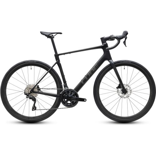 En mattsvart landsvägscykel med drop-styre, skivbromsar, smala däck och en lätt ram visas i sidovy mot en vit bakgrund. Cykeln har ett växelsystem med växelmekanism och en elegant, minimalistisk design.