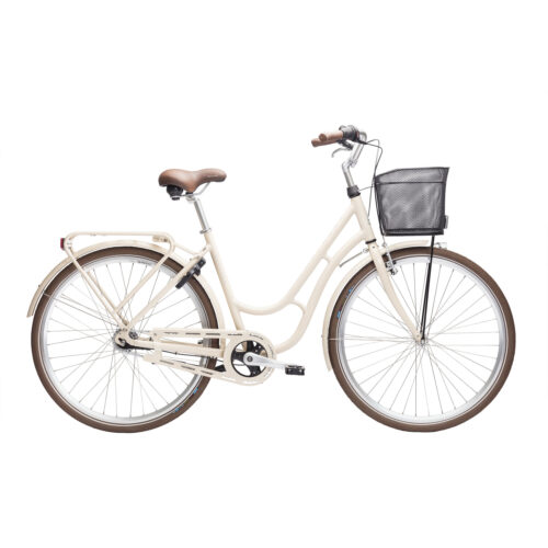 En krämfärgad Damcykel Monark Karin 7s, 28″, med brun sadel och handtag, nätkorg fram, pakethållare bak och stänkskärmar på båda hjulen, avbildad i profil mot en vit bakgrund.